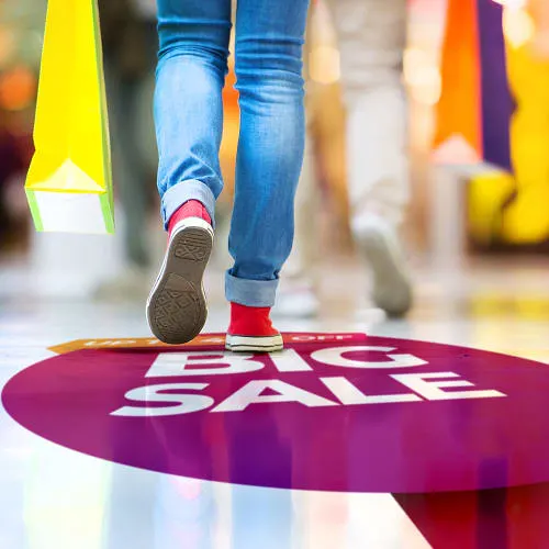 purple circle floor graphic with the words big sale in white with image of legs in jeans and red sneakers